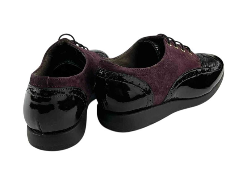 Vista por la parte de atrás de unos zapatos planos en piel ante y charol burdeos, con detales broge y suela antideslizante de goma.